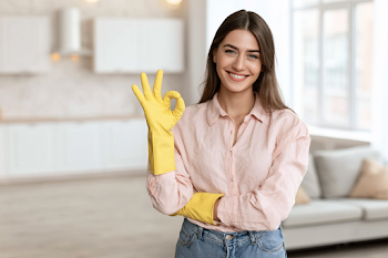 Cheerful Young Woman Making OK Gesture in Modern Apartment