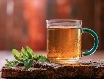Golden Herbal Tea in Clear Glass Mug with Mint