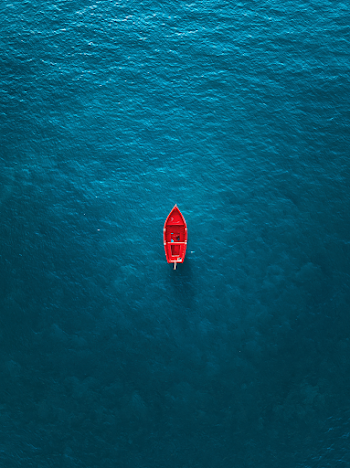 Serene Aerial View of a Red Boat on Crystal Clear Water