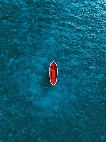 Serene Aerial View of a Red Boat on Crystal Clear Water