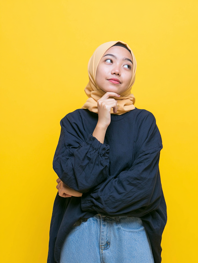 Contemplative Young Woman in Hijab on Yellow Background