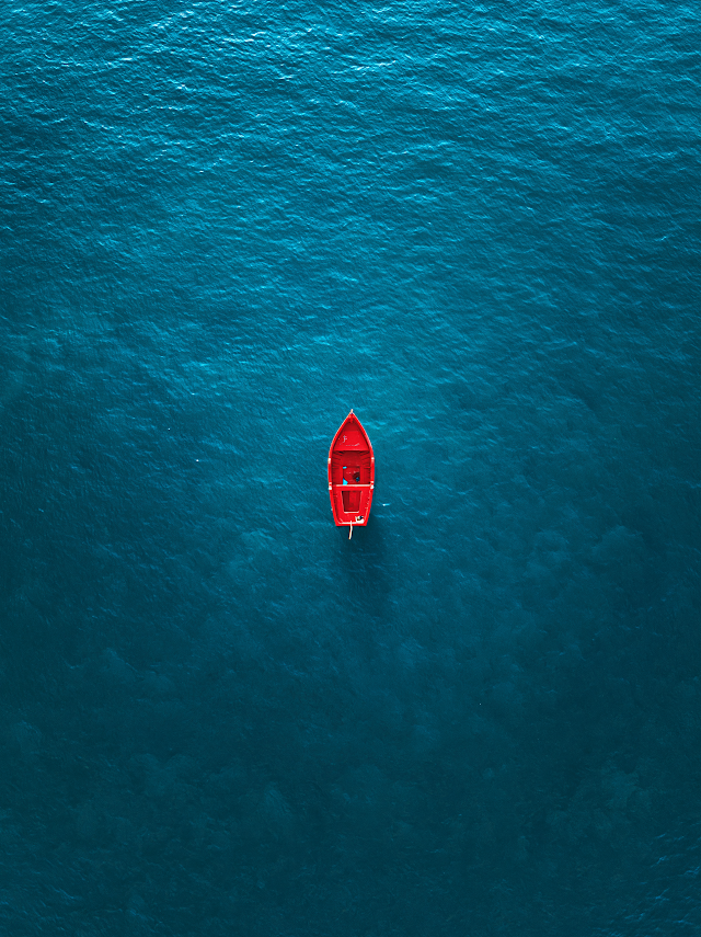 Serene Aerial View of a Red Boat on Crystal Clear Water